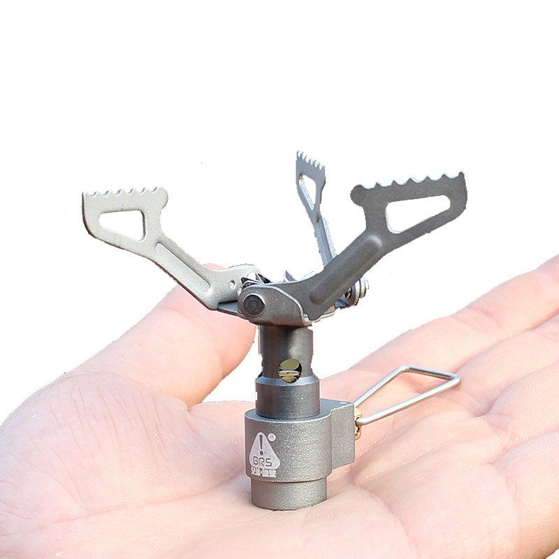 Tiny titanium canister stove held in a palm