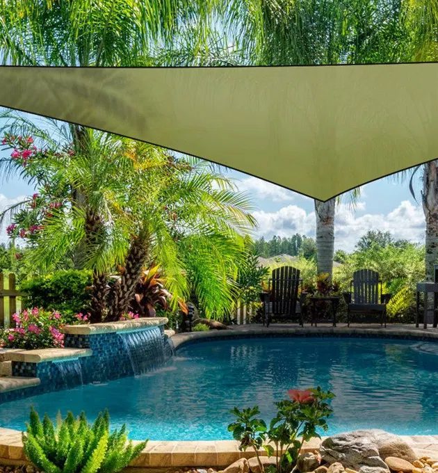 Army green triangle shade sail stretched over a backyard